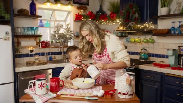 美しい金髪の女性は冬休み中にかわいい可愛い子供と自宅のキッチンで生地を調理します クリスマスイブのお祝いはRedを撮影しました シングルマザー 教える 小さな息子 冬の休暇中に料理 — ストック動画