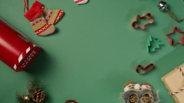 Kozalaklar, kırmızı Noel Baba posta kutusu, şekilli Noel kurabiyesi, el işi kağıtta hediye kutuları, yeşil arka planda dönen mumlar 4K. Renkli Noel arkaplanı. Kırmızı kamerada 360 derecelik dönüş açısı.