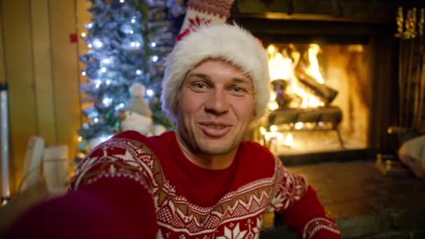 스웨터와 클로스 크리스마스 트리와 아늑한 벽난로 배경에 잘생긴 남자의 초상화 — 비디오