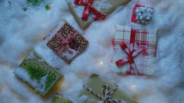 カラフルなギフトボックスと雪の漂流の下のツインリングガーランドで装飾されたクリスマスの白い雪の背景 ホリデー挨拶 セールスオファー クリスマスコピースペースRedカメラ撮影のトップダウンビュー — ストック動画