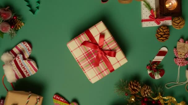 圣诞礼物 装饰品 红色圣诞信箱 饼干切出的形状旋转在躺平 红色相机镜头4K镜头 礼品盒 用缎子红色闪光缎带系在绿色背景的格子纸上 — 图库视频影像