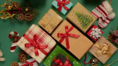 Yeşil arka planda kırmızı kurdelelerle bağlanmış renkli hediye kutularının genel görünümü. Lüks ikram, mücevher hediye, alışveriş, kara Cuma, Noel indirimi ve perakende konsepti kırmızı kamera döner görüntü 4K