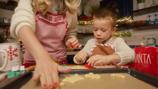 关闭拍摄过程烘焙传统圣诞姜饼 年轻的母亲教小男孩如何在烤箱前把面团饼干放在烤盘上 圣诞节 一家人在一起玩乐 — 图库视频影像
