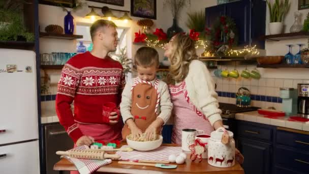 快乐的爱着现代家庭妻子亲吻丈夫 享受在一起做饭圣诞晚餐的时光 年轻漂亮的父母欢度寒假和小儿子在厨房吃饭 — 图库视频影像