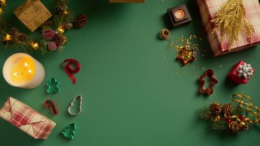 Sevilen insanlara tatil için bir hediye kutusu vermek. Düz yeşil arka plan, Noel süslemeleri, yakışıklı erkek elleri, kırmızı kurdeleli parlak altın parıltı kutusunu 4K kadına veriyor.