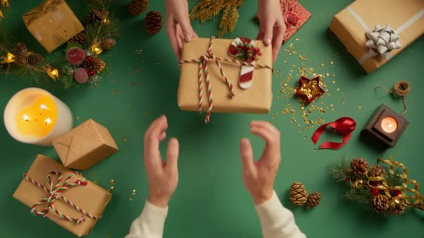 美しい若い女性の手は クリスマスの背景に男性にクラフトペーパーで手作りのスタイリッシュなシンプルなクリスマスギフトボックスを与えます 現在いる幸せな人たち 冬休みについて Diy ゼロ廃棄物コンセプト4K — ストック動画