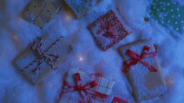 Kış büyülü, karlı bir Noel gecesi 4K 'nin en üst düzey arka planı. Bayram arka planında hediye kutularının üzerinde hafif kar taneleri uçuşuyor. Kırmızı ve beyaz Noel hediye kutuları kar yığınının üzerinde yatıyor