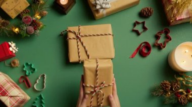 Üst Manzara. Kırmızı kazaklı güzel kadın elleri. El işi kağıdıyla Noel hediyeleri süslüyor. Tatil sezonu, kış harikalar diyarı, fotokopi alanı ağır çekim. El sanatları arka planında Noel süslemeleri