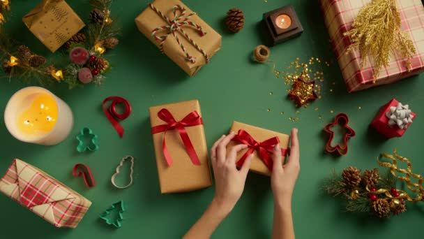 クリスマスプレゼントを包み込まない手 黄金の箱を開けるために光沢のある絹の赤いリボンを引っ張る若い女性の手の空想的な眺め パッキング 休日の買い物 満足した消費者 販売の提供の背景を提示して下さい — ストック動画