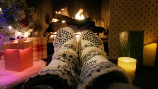 キャビン4Kの居心地の良い暖炉によって伝統的な冬のパターンが付いている木製の靴下の視野フィートを閉めて下さい 暖かい火でリラックスして足を温める 冬とクリスマスの休日のコンセプトRedカメラショット — ストック動画