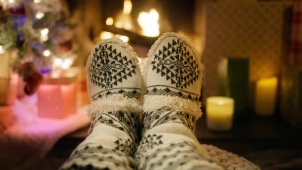 最初の人間のクローズアップビュー4Kフィートは 伝統的な冬のパターンで暖かいウールの靴下を着用し クリスマスイブの暖炉のそばに横たわっています フォレストキャビンの居心地の良い冬の季節の雰囲気 — ストック動画