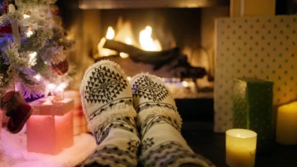 フォレストキャビン4Kの居心地の良い冬の季節の雰囲気 最初の人間のクローズアップビュー 伝統的な冬のパターンと暖かいウールの靴下を身に着けている人足の4K映像 クリスマスイブの暖炉のそばに横たわる — ストック動画