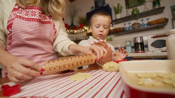 教える かわいい クッキー生地 カイスターマス パターン ローリング クッキーを準備する母親を助けるおかしい子供の少年 自宅でキッチンで家族料理のベーキングペストリー — ストック動画