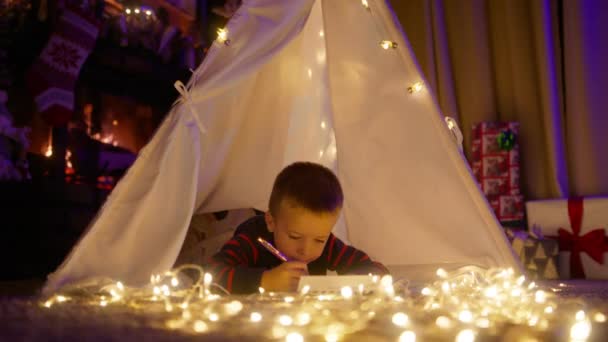 Милый Мальчик Пишет Свои Пожелания Письме Санта Клаусу Сказочной Атмосфере — стоковое видео