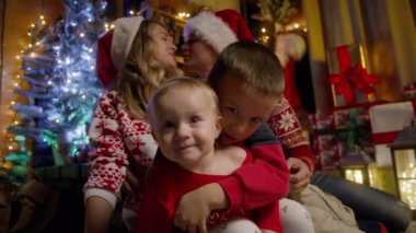 Sevimli küçük çocuk Noel arifesinde evde oyun oynuyor, sarılıyor ve küçük kızı öpüyor. Mutlu aile anne, baba ve sevimli kardeşler birlikte eğleniyorlar. Kış tatillerinde güzel anların tadını çıkarıyorlar.