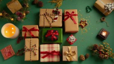 Kadın ve erkek elleri masadan birçok renkli hediye kutusunu alır. Güzel hediye kutularıyla dolu, yeşil arka planda ve Noel süslemeleriyle dolu bir daire. Genel görünüm hediye arkaplanı