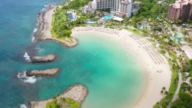 Manzaralı mavi bir sahil gölü olan Drone aile oteli. Hawaii 'deki Oahu Adası' ndaki Ko Olina tatil beldelerinde. Palmiye ağaçları, egzotik seyahat cenneti 4K. Sinematik lüks deniz manzaralı otel.