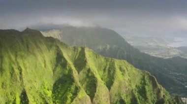Güneşli gündoğumunda dramatik Hawaii bulutlu havası. Cennete giden merdiven tehlikeli yürüyüş yolu. Oahu Adası 'ndaki Haiku Merdivenleri' nin tepesinden görüntü. 4K dikey eğimli dik yamaçlı destansı yeşil dağlar.
