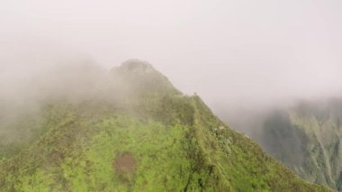 Bulutların arasından cennete giden tehlikeli yürüyüş patikasına uçuyor. Oahu Adası 'ndaki Haiku Merdivenleri' nin tepesinden görüntü. 4K dik tepe ile destansı yeşil dağ zirveleri. Havai 'de bulutlu bir günde dramatik hava.