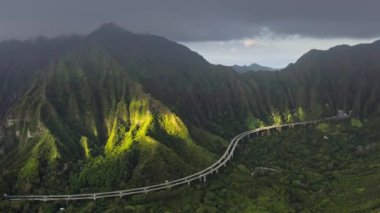 Dik yeşil dağdaki tünelden tünele giden hava manzaralı arabalar. Eyaletler arası H3 otoyolu Amerika 'nın en pahalı otoyolu. Oahu adasının ana yolu nefes kesici manzarası 4K güzel Hawaii doğası