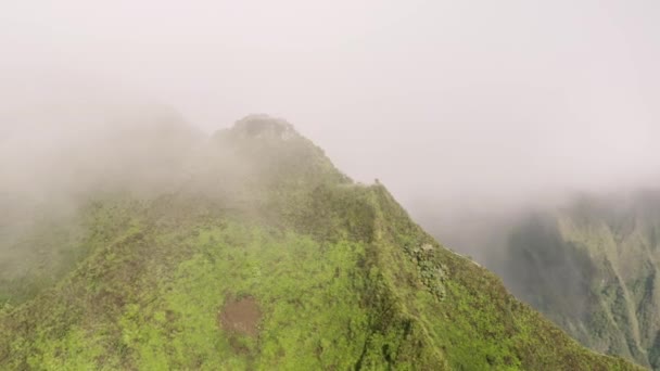 階段を越えて雲を飛んで天国への危険なハイキングトレイル オアフ島の俳句階段の上からの眺め 急な尾根4Kを備えたエピックグリーン山頂 ハワイの曇りの日の劇的な空中 — ストック動画