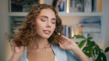 Kadın güzelliğinin tadını çıkarıyor, kendine güveni yüksek. Yakından bakınca güzel yüz seksi gülümseyen kadın esmer kıvırcık saçlara dokunuyor. Kameraya bakan muhteşem bir kızın portresi. Gülümseyen beyaz kadın yüzü