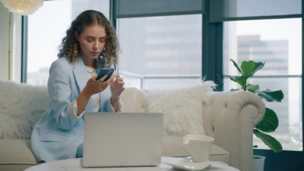 Συγκεντρωμένη Νεαρή Επιχειρηματίας Κρατώντας Smartphone Κάθεται Στον Καναπέ Στο Γραφείο — Αρχείο Βίντεο