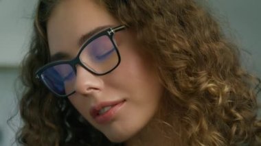 Mavi gözlü, gülümseyen, kendine güvenen güzel bir Ukraynalı kadın. Kırmızı kameraya bakıyor. Ofiste yalnız poz veriyor. Mutlu milenyum etnik kökenli kız öğrenci profesyonel portreyi yakın çekimde 4K