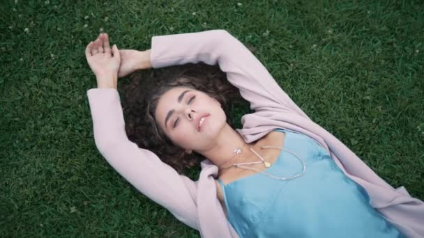 Redカメラで撮影されたクリエイティブなアートコンセプト 緑の草の上に横たわるファッションビューティモデル 屋外の公園で夏を楽しんでいる美しい女性 青いドレスでリラックスした若い女性が手を動かします — ストック動画