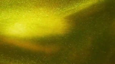 Suda çözünen yeşil ve sarı mürekkebin zaman aşımı etkisi. Soyut renkli arkaplan. Işıltılı altın boya dalgaları. Yaratıcı duvar kâğıdı. Suyun altında renklerin sıçraması, 4k görüntü