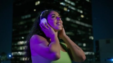 Şehir merkezinde müzik dinleyen genç ve güzel melez bayan hippi, açık havada gecenin tadını çıkartıyor. Rahat, seksi Afro-Amerikan kadın, kulaklıklı, gece yarısı tek başına dans ediyor.