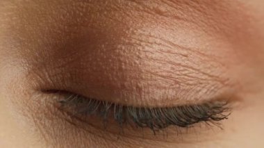 Blue iris natural beauty looking RED camera. Opening and smiling blue eyes beautiful girl. Fashion model, natural day makeup with mascara on eyelashes. Macro close up of light blue female eye wrinkles