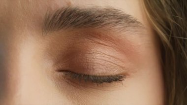 Close up of womans Face. Young attractive girl opening her Beautiful blue azzure eyes. Natural Beauty with thick eyebrows. Gorgeous woman with long Eyelashes and Attractive face. Slow motion beauty 4K