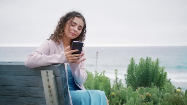 Happy Kręcone Dziewczyna Siedzi Drewnianej Ławce Parku Oceanu Patrząc Ekranie — Wideo stockowe