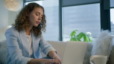 Modern ofis alanında dizüstü bilgisayar kullanan açık mavi takım elbiseli zarif profesyonel bir iş kadını. Kentsel arka planda kurumsal teknoloji aygıtı üzerinde çalışan odaklanmış iş kadını yöneticisi