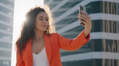 Mutlu çift ırklı kadın selfie çekiyor, selfie çekiyor ve öpüşüyor, gün batımında sosyal medyada paylaşıyor. Moda yaşam tarzını etkileyen blogcu sinematik güneş merceklerinde cep telefonu kullanıyor
