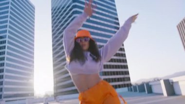 Kentsel fütüristik arka planda yavaş çekimde dans eden havalı, çok ırklı genç bir kadın. Moda kıyafetlerle poz verip sokak dansı hareketleri sergileyen muhteşem çeşitli modelin sinematik kırmızı kamerası.