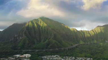 4K Hawaii manzaralı sinematik yol havası. Dik yeşil dağda tünelden tünele giden insansız hava aracı manzaralı araçlar. Oahu Adası 'na doğru H3 otoyolunda nefes kesici bir viraj.
