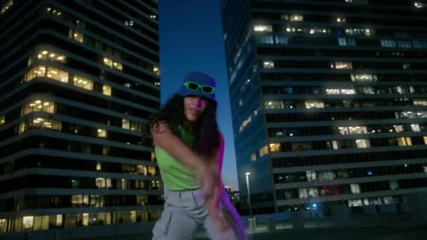 在屋顶的迪斯科舞会上 活跃而美丽的混血女子俱乐部 在霓虹灯下跳舞的迷人女性的画像 性感酷的女孩凝视着市中心的夜景 — 图库视频影像