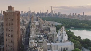 ABD turizm arka planı 4K New York havayolları. Dünyaca ünlü Central Park manzaralı prestijli konut binalarına nefes kesici bir manzara. Yaz akşamı sinematik Manhattan panoraması. Destansı New York şehir manzarası