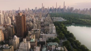 Yaz akşamı sinematik Manhattan panoraması. Efsanevi New York şehri manzarası. ABD turizm arka planı 4K New York havayolları. Dünyaca ünlü Central Park manzaralı prestijli konut binalarına nefes kesici bir manzara.