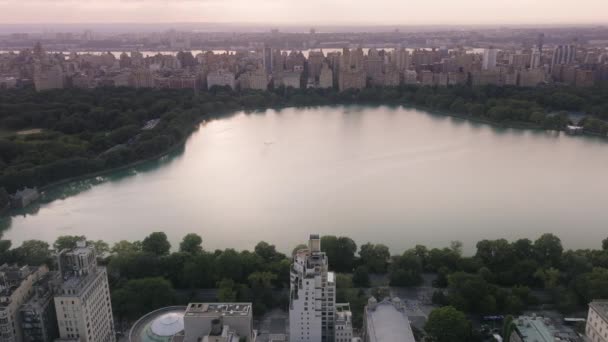 市区公园夏季旅游 中央公园上方的史诗般的粉色落日 风景秀丽的湖面映衬着美丽的天空 绿城中央公园的空中 4K史诗全景曼哈顿 纽约市中心的背景 — 图库视频影像