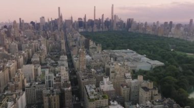 Arka plandaki Manhattan gökdelenleri yeşil şehir parkı. Yeşil park ve binalarla çevrili güzel bir göl. Sinematik Central Park manzara manzarası. New York şehir merkezinin 4K hava görüntüsü
