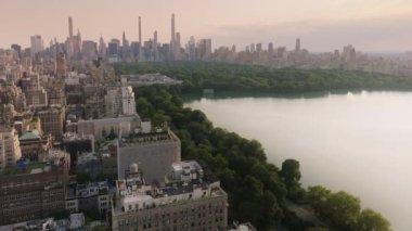 Dünyaca ünlü Central Park manzaralı prestijli konut binalarına nefes kesici bir manzara. Yaz akşamı sinematik Manhattan panoraması. Efsanevi New York şehri manzarası. ABD turizmi arka planı 4K New York Havayolları