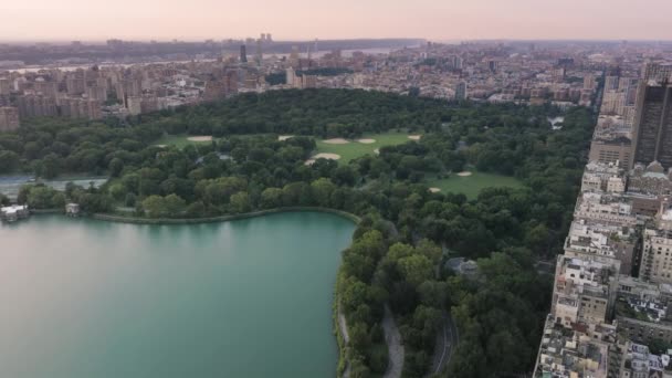 美丽的湖水被绿色的公园和纽约曼哈顿上城的建筑物环绕着 纽约市中心的中央公园4K航拍 绿城中央公园 旅游背景美国影片 — 图库视频影像