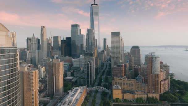 ゴールデンサンセットの間 マンハッタン下部の金融地区の息をのむようなパノラマ モーションバックグラウンドの風光明媚なモダンな高層ビルとピンクの雲を持つニューヨークのエピック航空 ロックフェラーパーク アメリカ — ストック動画