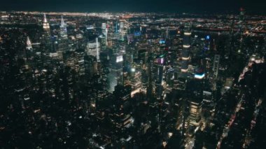 Manhattan New York City 'nin üstündeki hava manzarası. Gece aydınlanan Times Meydanı 'na doğru nefes kesici bir uçuş. Uzaydan görünen büyük dijital ekranlarda modern reklamlardan kaynaklanan ışık kirliliği