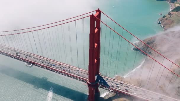 空中头顶为红色金门地标 背景为旧金山绿山 在美国青太平洋上空 有金色落日的悬索桥高塔周围飞行的无人机 — 图库视频影像