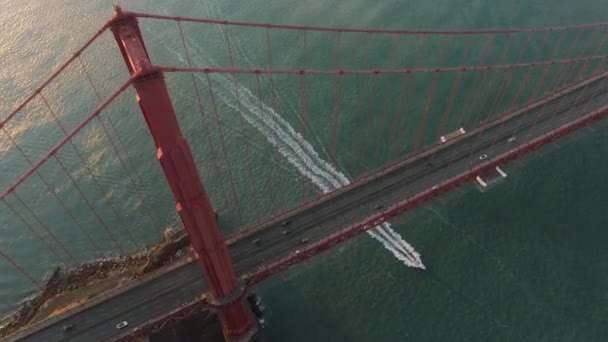 在金黄色日出时分 在旧金山湾 空中环绕着红色的桥塔 车流和游艇飞驰而过 加州4K鸟瞰西海岸著名的金门大桥旅游地标 — 图库视频影像