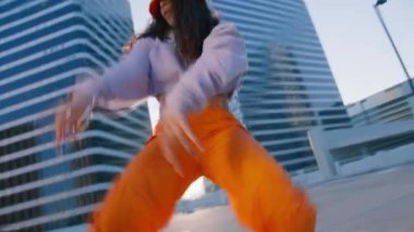Seksi Twerk ve serbest stil dansçısı şehrin arka planında altın günbatımında dans figürleri yapıyor. Afrikalı Amerikalı genç bir kadın çatıda şehvetle dans ediyor.